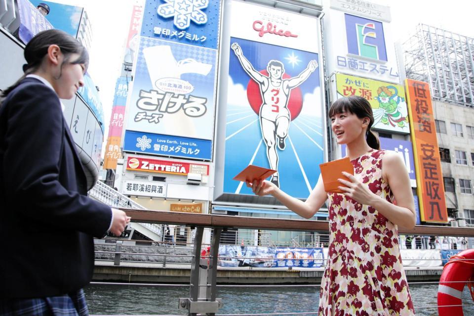 道頓堀グリコサイン前で、道行く人にラブレターを手渡しする綾瀬はるか（右）　©２０２６　映画「人はなぜラブレターを書くのか」製作委員会