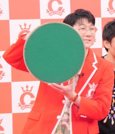 優勝トロフィーの滑り止めがついた底を見せるロングコートダディ・堂前透