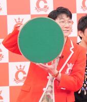 優勝トロフィーの滑り止めがついた底を見せるロングコートダディ・堂前透