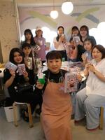 シール帳を掲げる天童よしみ、（後ろの）来店客＝東京・しぇあぷく原宿店