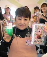 シール帳を掲げる天童よしみ、（後ろの）来店客＝東京・しぇあぷく原宿店