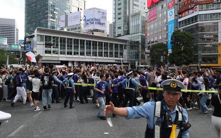 交通整理をする警察官と日本代表の勝利に盛り上がるサポーター（撮影・佐々木彰尚）