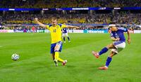 試合終了間際、クロスを上げる長友佑都（右）＝共同