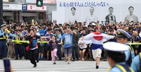 日本が１次Ｌ突破を決め、警官の制止を振り切って渋谷スクランブル交差点を駆け出す人々（撮影・伊藤笙子）