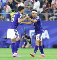 引き分けで決勝トーナメント進出を決め渡辺（左）と熱くタッチを交わす長友＝２５日、ダラス