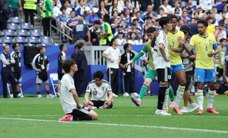 ブラジルに敗れピッチに座り込む日本代表・上田綺世（奥）。右では冨安健洋がブラジルの選手たちから声をかけられる＝６月２９日、ヒューストン