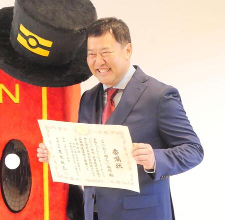 委嘱状を手に笑顔を見せるとにかく明るい安村