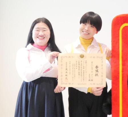 委嘱状を手に笑顔を見せるガンバレルーヤ