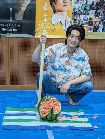 割ったスイカを前に笑顔を見せる真田ナオキ
