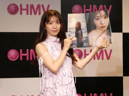 写真集を持ち撮影に応じる真山りか