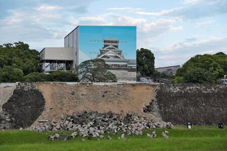 崩落した熊本城の石垣。奥は素屋根で覆われた宇土櫓（うとやぐら）＝29日午後６時40分、熊本市