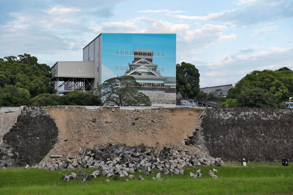 崩落した熊本城の石垣。奥は素屋根で覆われた宇土櫓（うとやぐら）＝29日午後６時40分、熊本市