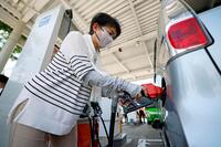 熊本県八代市のガソリンスタンドで給油する女性