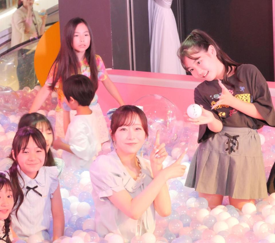 ボールプールに１つだけ隠された自身のサイン入りボールを見つけた小学生と写真に収まる真中まな（中央）