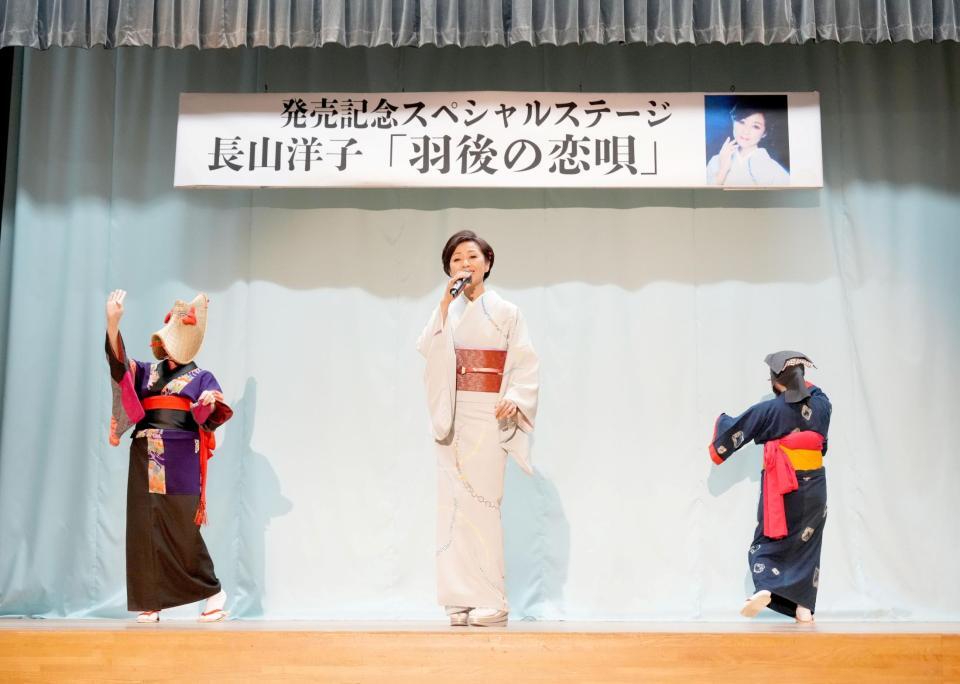 最新曲の舞台で歌声を響かせる長山洋子（中央）