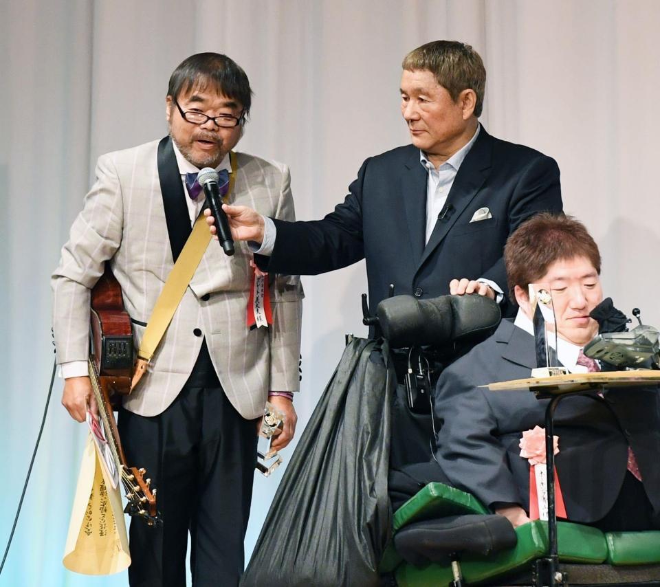 東京スポーツ映画大賞で特別芸能賞を受賞し、ビートたけし（中央）からマイクを向けられるグレート義太夫さん（左）＝２０１９年２月
