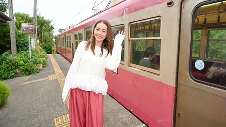 走る電車を背に笑顔を見せる熊切あさ美
