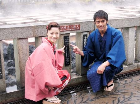 　プレートを指さす阿部寛（右）と上戸彩＝群馬県・草津温泉