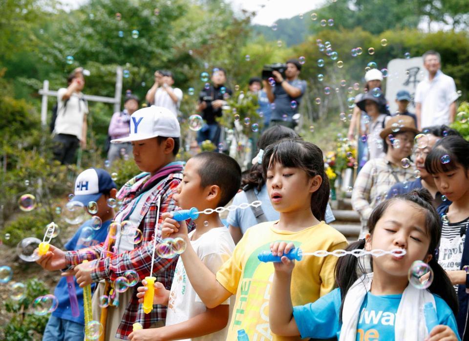 　「御巣鷹の尾根」にある「昇魂之碑」の前で、犠牲者を悼みシャボン玉を飛ばす子どもたち＝群馬県上野村