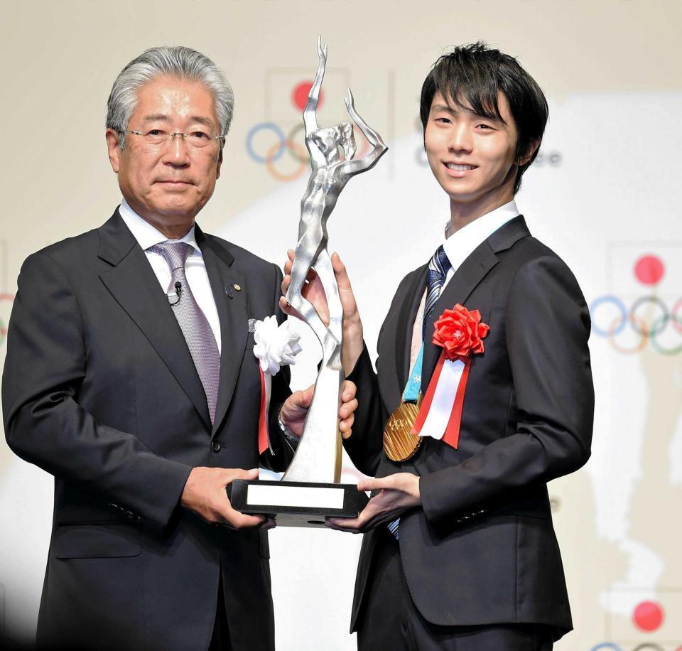　日本オリンピック委員会の竹田恆和会長（左）からトロフィーを受け取り、笑顔を見せる羽生結弦