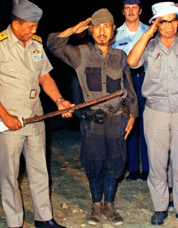 　１９７４年３月、軍刀を渡し敬礼をする元陸軍少尉の小野田寛郎氏（中央）＝フィリピン・ルバング島