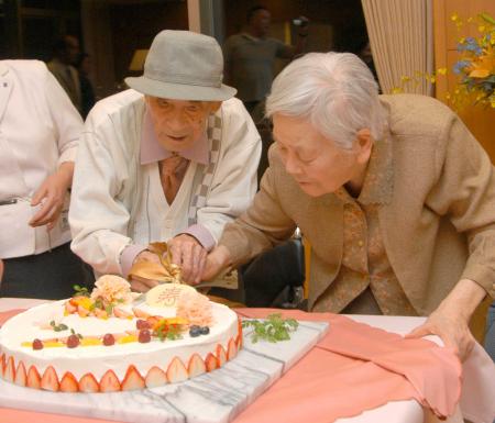 　１００歳を記念するパーティーでお祝いのケーキを前にする、まど・みちおさん。右は夫人の寿美さん＝２０１０年４月、東京都稲城市
