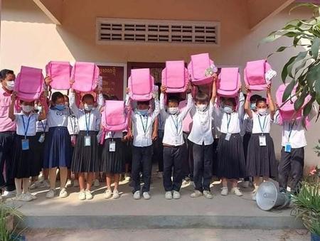 贈られたラクサックを掲げるカンボジアの小学生たち。「重さ」より「暑さ」対策で歓迎されているという