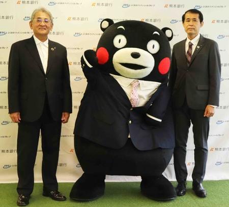 東京オフィスの発表会見で、熊本銀行の野村俊巳頭取（左）と熊本県の内田清之東京事務局長と記念撮影するくまモン