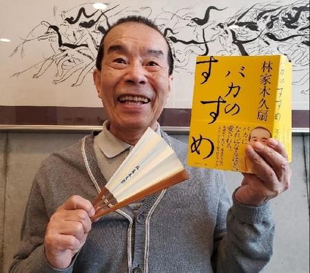 事務所に掲げた絵の師匠・清水崑さんの作品前で、著書「バカのすすめ」を手にする林家木久扇。８５歳の記念落語会を開催する＝都内