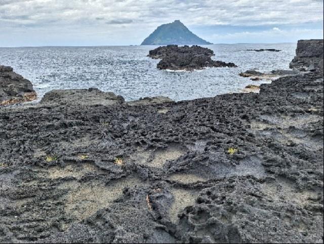 火山から流れた溶岩で形成された八丈島の海岸。向かいには八丈小島＝東京・八丈町