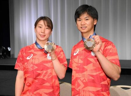 パリ五輪から帰国し、メダルを手に笑顔を見せる渡辺勇大（右）・東野有紗ペア＝東京・羽田空港