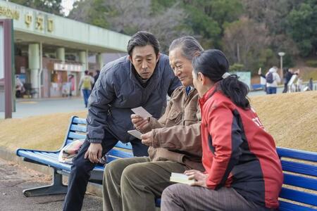 万博公園の入り口近くで、息子・聖人（北村有起哉・左）たちと楽しそうな永吉（松平健）