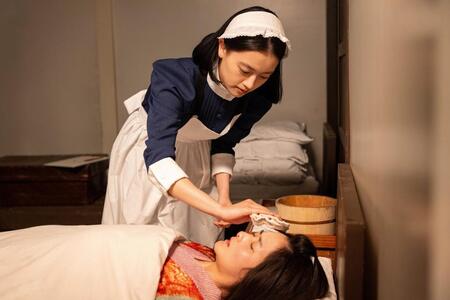 命の助かった女郎・夕凪（村上穂乃佳）の看護にあたる直美（上坂樹里）