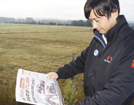 　地元紙に目を通し満足げな表情を浮かべる池江師