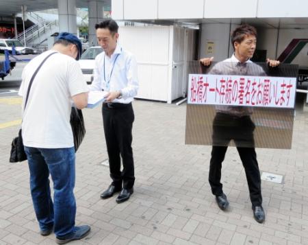 ＪＲ船橋駅前で署名活動を行う永井大介支部長（左）と青山周平
