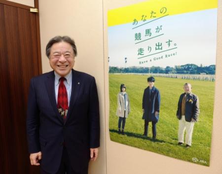 　２０１５年のポスターを笑顔で紹介するＪＲＡ新理事長の後藤正幸氏（撮影・開出　牧）