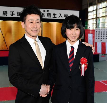 競馬学校に入学し父で元騎手の今村康成助手（左）と笑顔で握手する今村聖奈＝千葉県白井市のＪＲＡ競馬学校（撮影・三好信也）