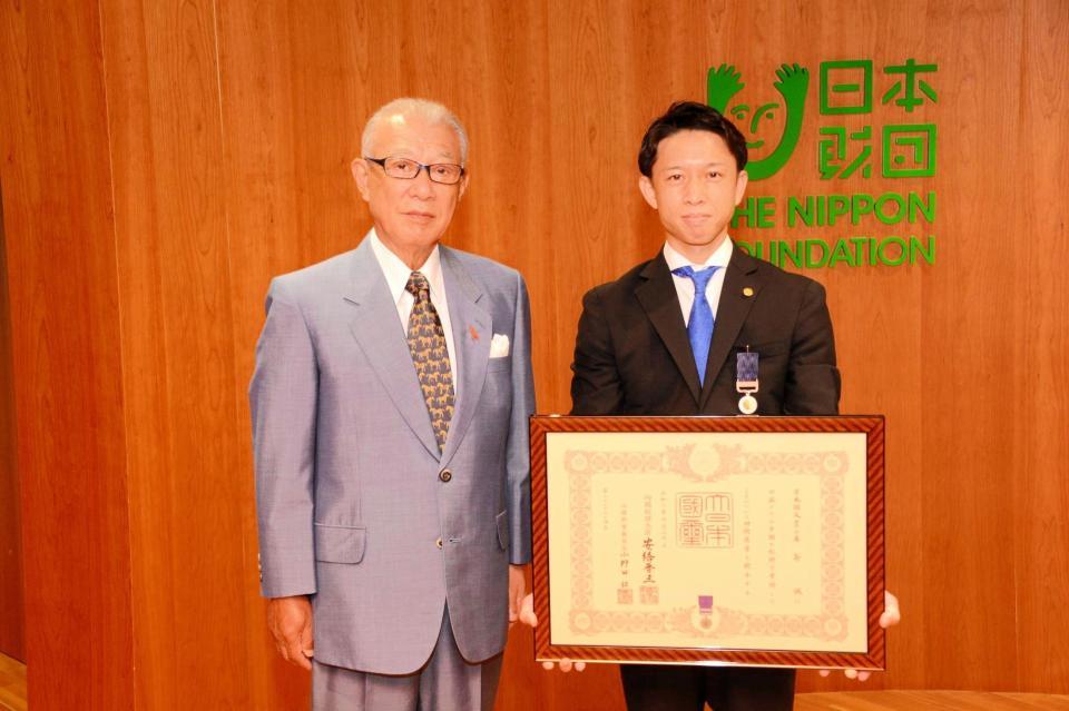 日本財団の笹川陽平会長（左）から紺綬褒章を伝達された毒島誠