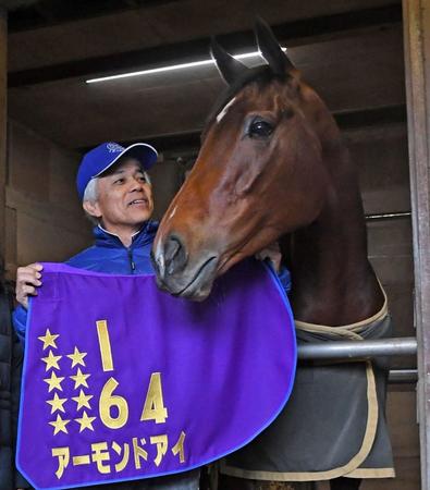 出来たてほやほやのＧ１９勝目の星が入ったアーモンドアイのゼッケンを笑顔で披露する国枝栄調教師＝美浦トレセン（撮影・三好信也）