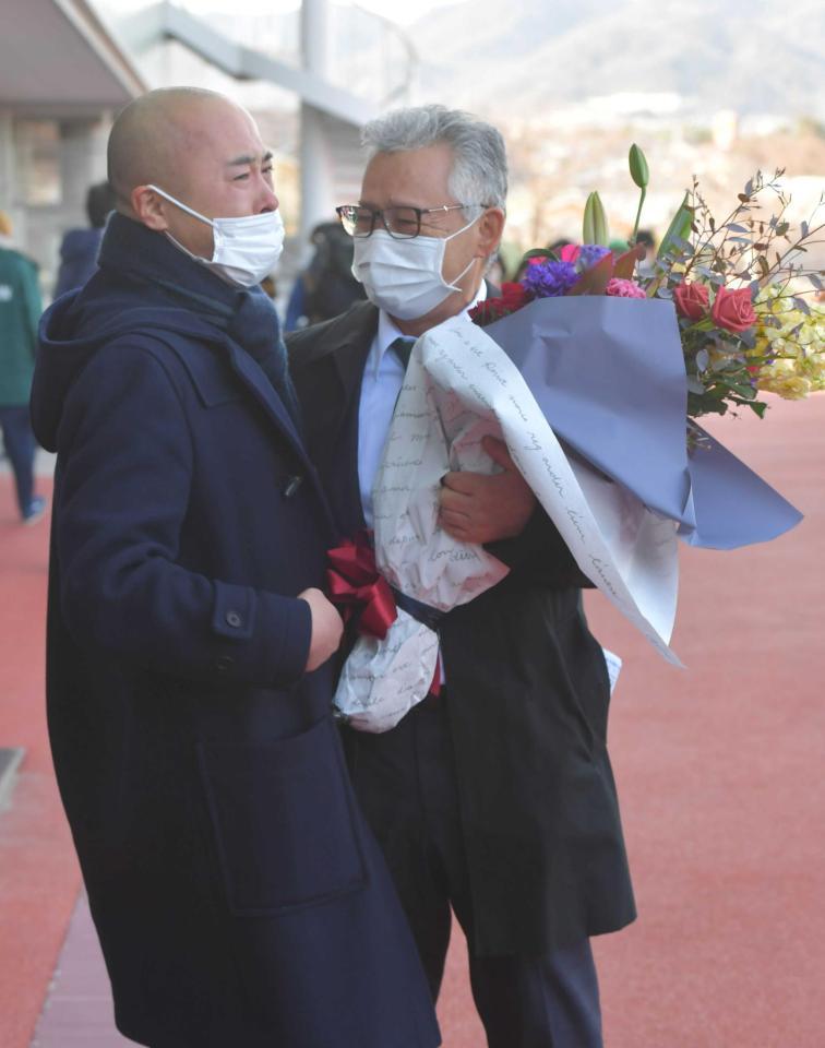 　息子の公一師（左）から花束を贈られた石坂正師＝撮影・石湯恒介