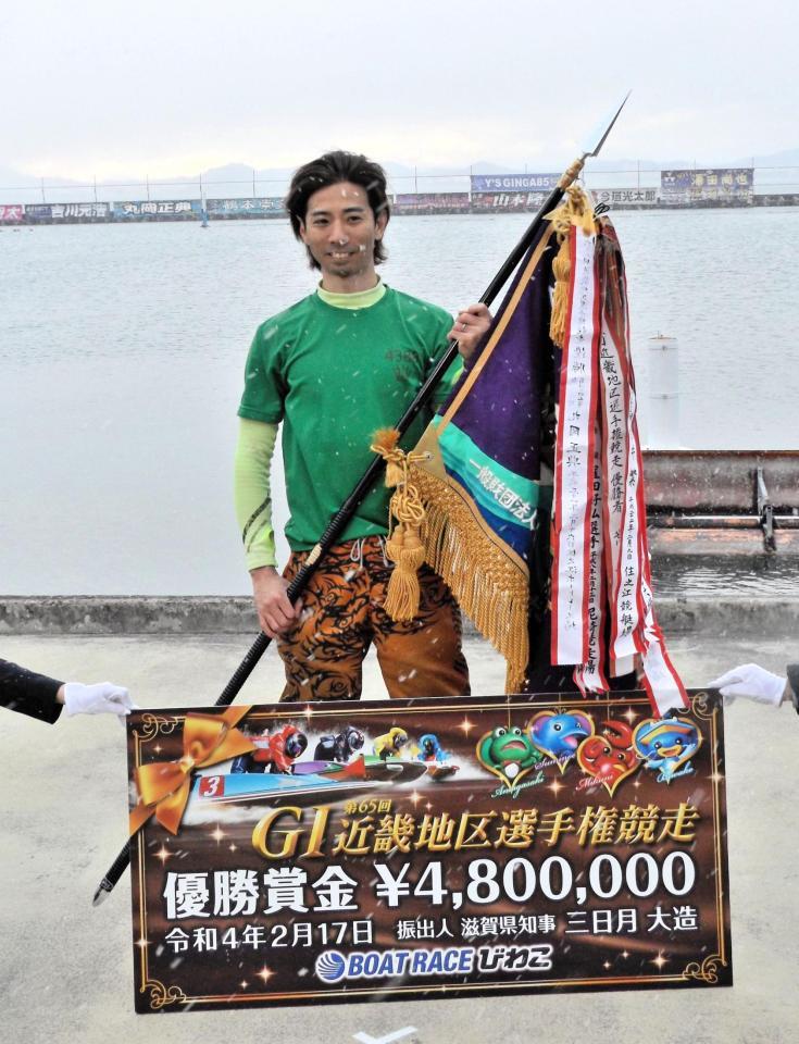 雪が舞う中で優勝旗を手に喜ぶ是沢孝宏