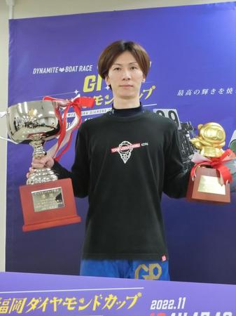　優勝トロフィーとペラ坊ブロンズを掲げて笑顔の岡崎恭裕