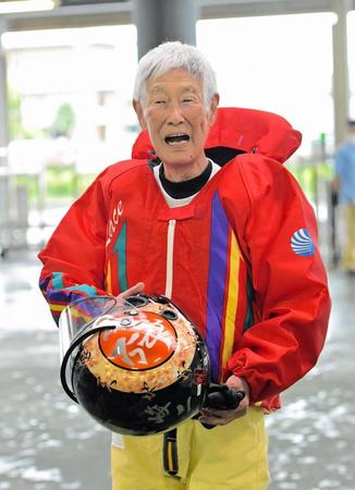 　赤のカポックを身にまとい現役時代のヘルメットを手にする加藤峻二さん