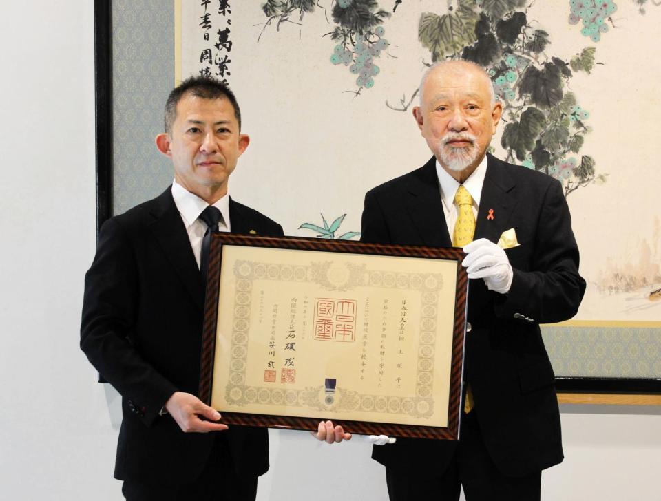 　紺綬褒章を受章した桐生順平の代理で褒状を受章した瓜生正義（左）