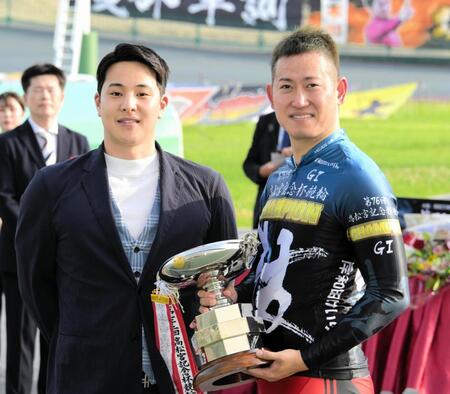 高松宮記念杯を制し優勝杯を手に笑顔の脇本雄太と記念写真に収まる元五輪水泳代表の瀬戸大也（左）＝岸和田競輪（撮影・金居みつよし）