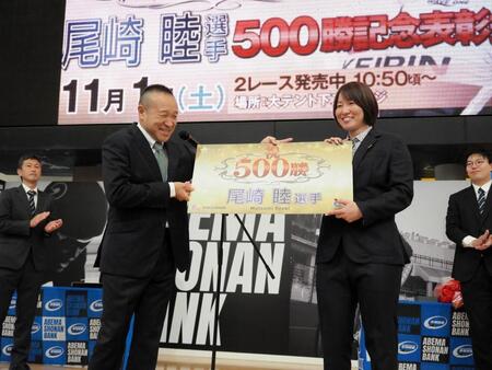 　５００勝記念パネルを高木隆弘支部長（左）からもらう尾崎睦