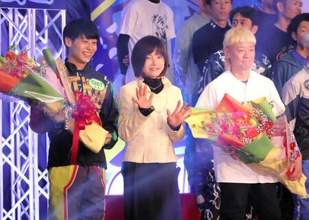 花束贈呈のプレゼンターとして登壇した日高逸子さん（中央）。左は石本裕武、右は湯川浩司