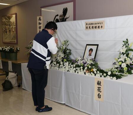 伏見俊昭さんの献花台に手を合わせるファン（撮影・中田匡峻）