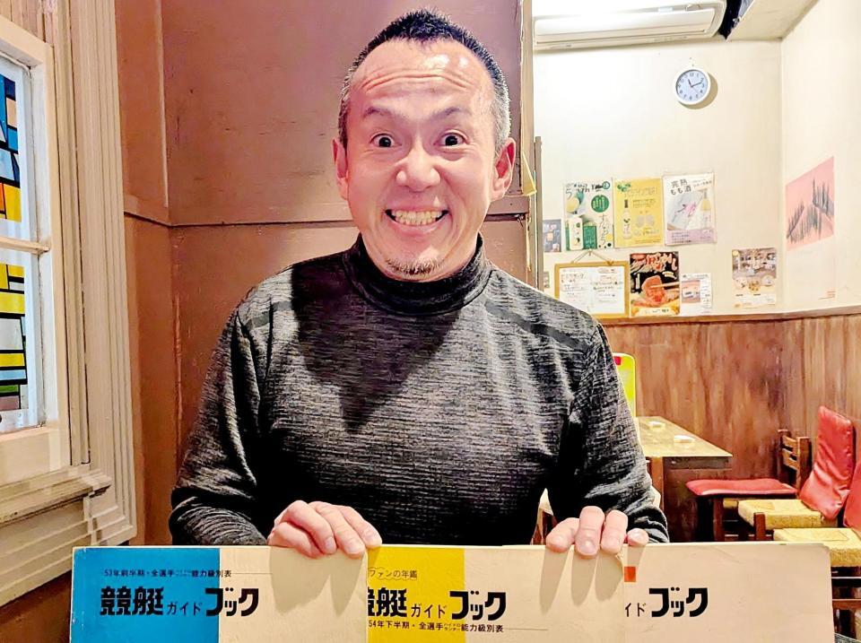 　古いボートレースの文献を持ち笑顔の増田鉄男