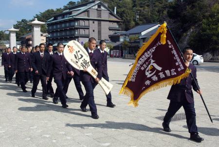 　選抜旗と大しゃもじを手に厳島神社に必勝祈願に向かう広陵ナイン＝廿日市市・宮島